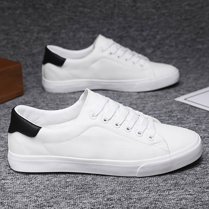 Parę męskich białych sneakersów na szarej teksturowanej powierzchni