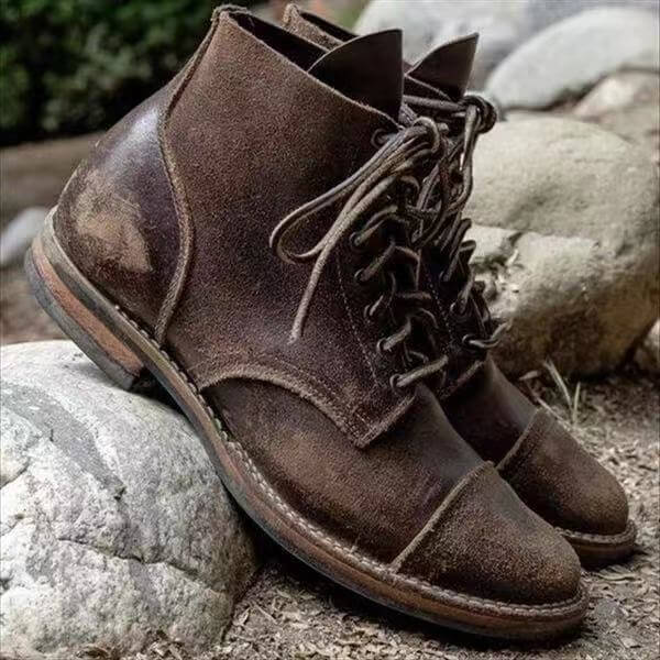 Męskie skórzane buty w ciemnobrązowym odcieniu prezentowane na kamienistym podłożu