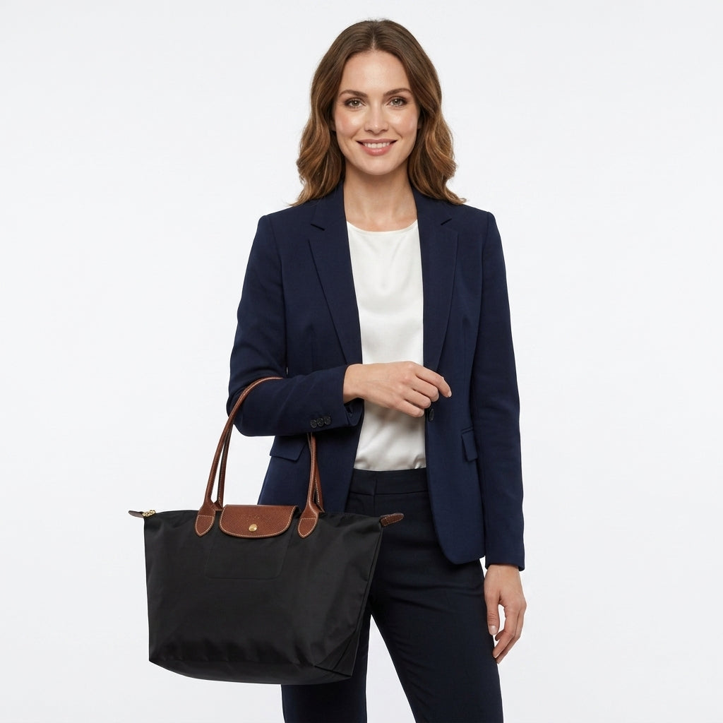 Kobieta w granatowej marynarce trzymająca czarną torbę shopper na ramię