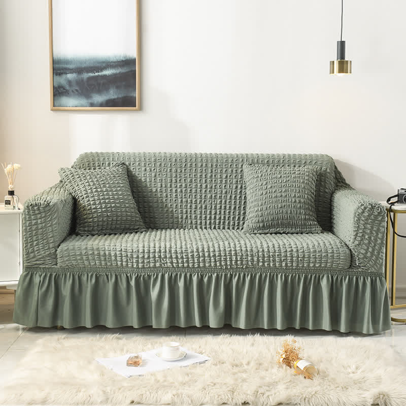 Zielona sofa z pokrowcem z falbanką w jasnym salonie