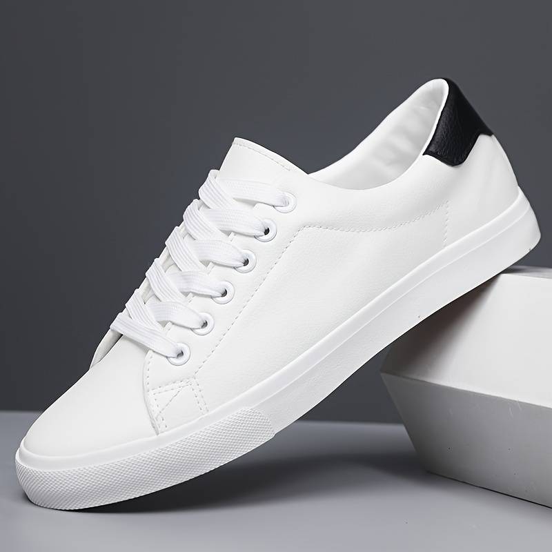 Boczne ujęcie męskich białych sneakersów na minimalistycznym podwyższeniu