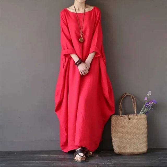 Kobieta stojąca w czerwonej sukience maxi o luźnym kroju i stylu boho
