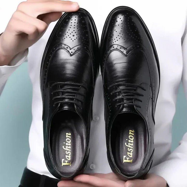 Czarne męskie buty wizytowe Lorenzo z ozdobnymi przeszyciami prezentowane w dłoniach