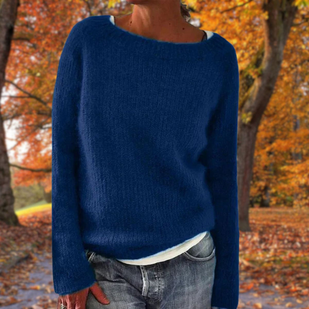 Kobieta w niebieskim dzianinowym swetrze oversize na tle jesiennych drzew