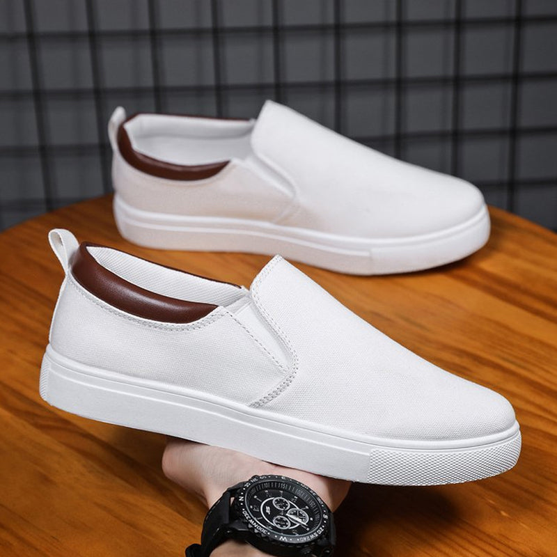 Białe męskie wsuwane sneakersy z brązowym wykończeniem trzymane w dłoni