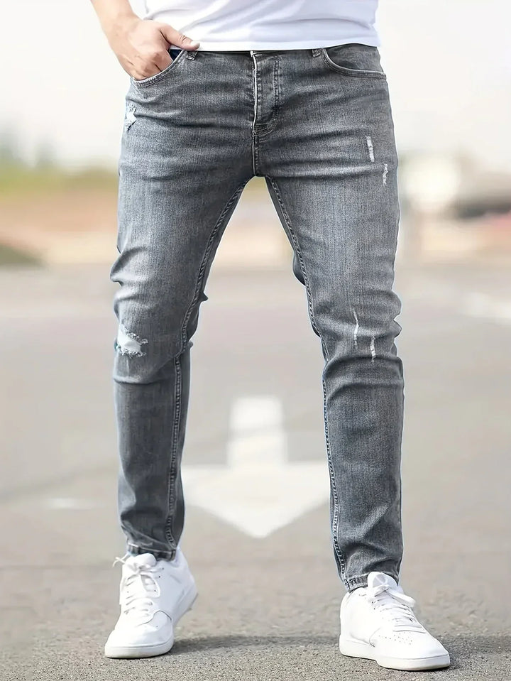 Mężczyzna w szarych męskich jeansach slim fit prezentujący nowoczesny krój