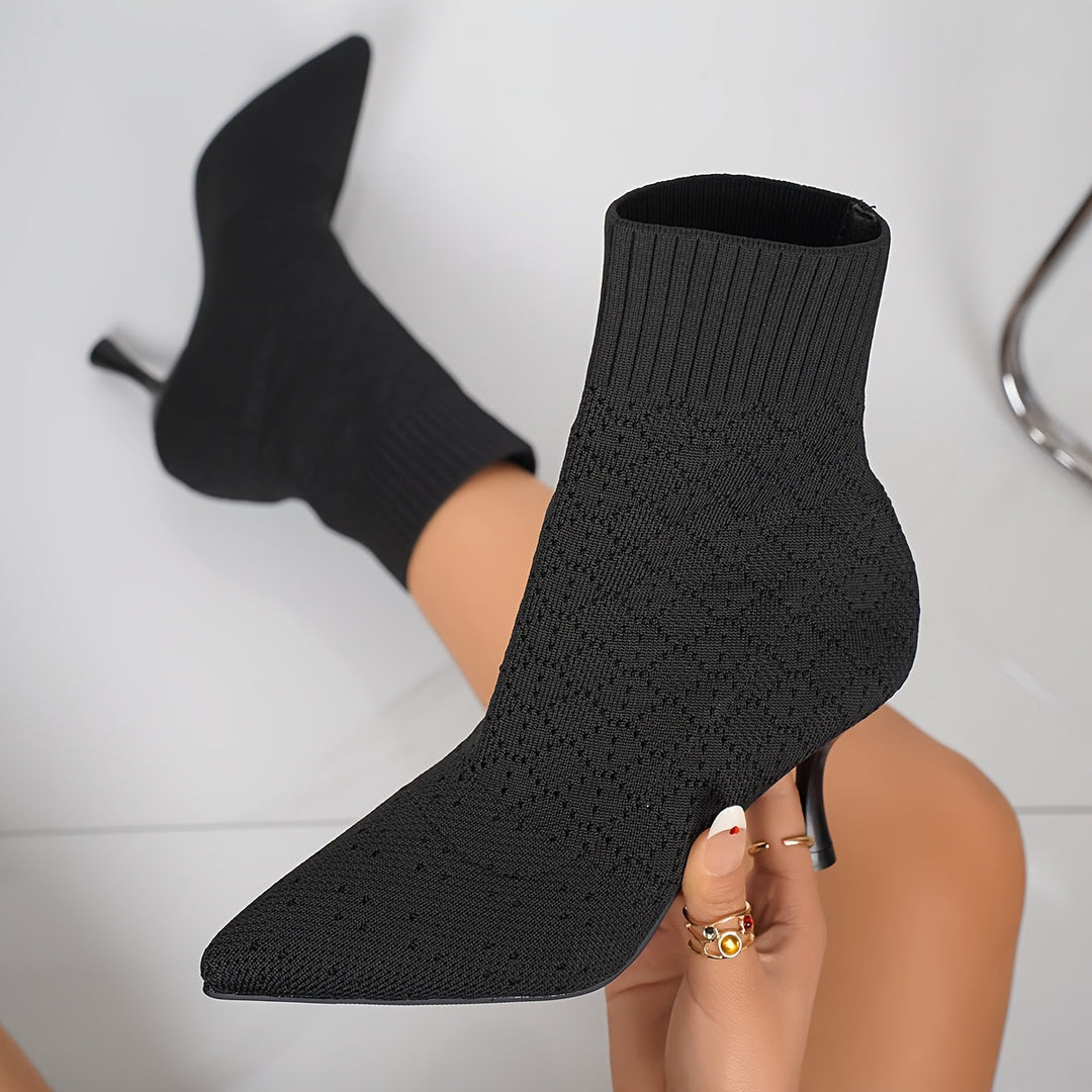 Czarne damskie botki na szpilce typu slip-on z zaokrąglonym czubkiem prezentowane w dłoni
