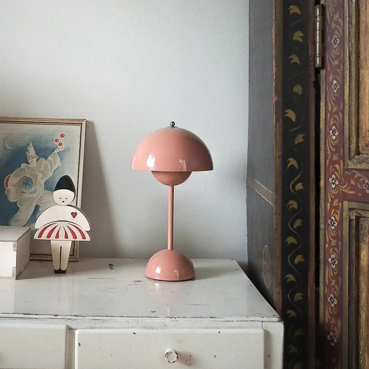 Różowa lampa stołowa LED stojąca na białej komodzie w minimalistycznym wnętrzu