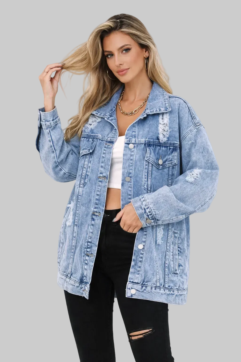 Modelka prezentująca jasnoniebieską damską kurtkę jeansową oversize z przetarciami