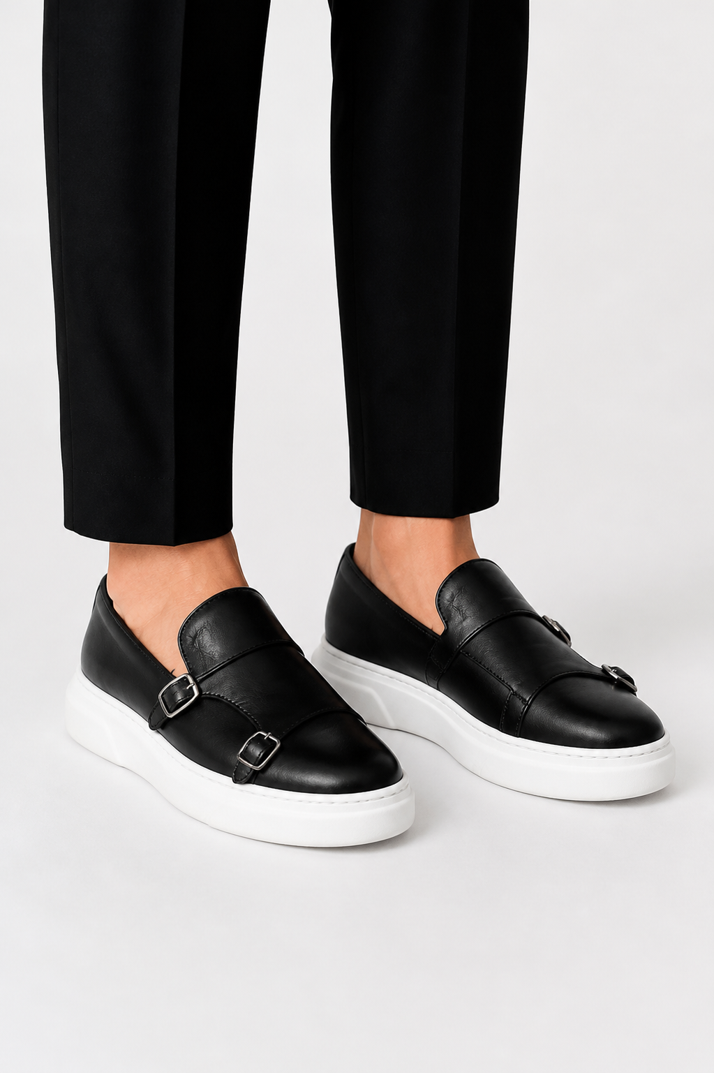 Męskie czarne mokasyny slip-on z klamrami i białą podeszwą na nogach