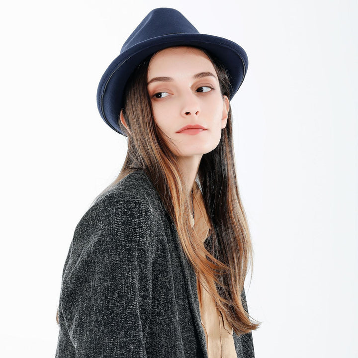 Kobieta prezentująca elegancki granatowy damski kapelusz fedora z ozdobną wstążką w stylizacji miejskiej