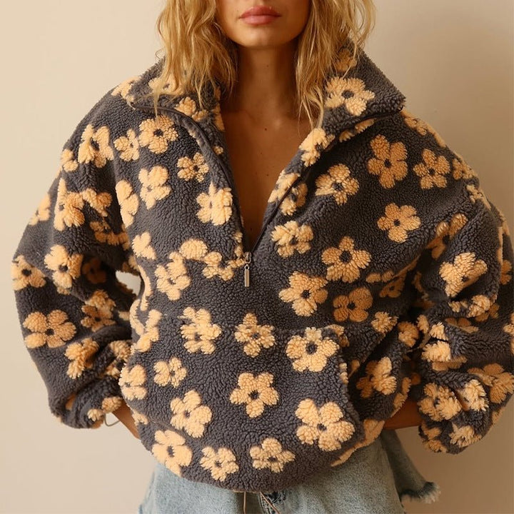 Kobieta w szarej kurtce polarowej oversize z żółtym motywem kwiatowym i zamkiem