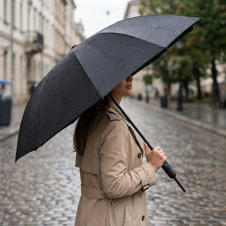 Kobieta trzymająca duży czarny odwrócony parasol na ulicy podczas deszczu