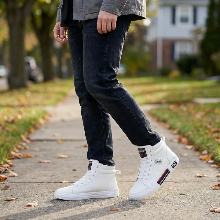 Mężczyzna w dżinsach prezentujący białe wysokie sneakersy Tommie na chodniku