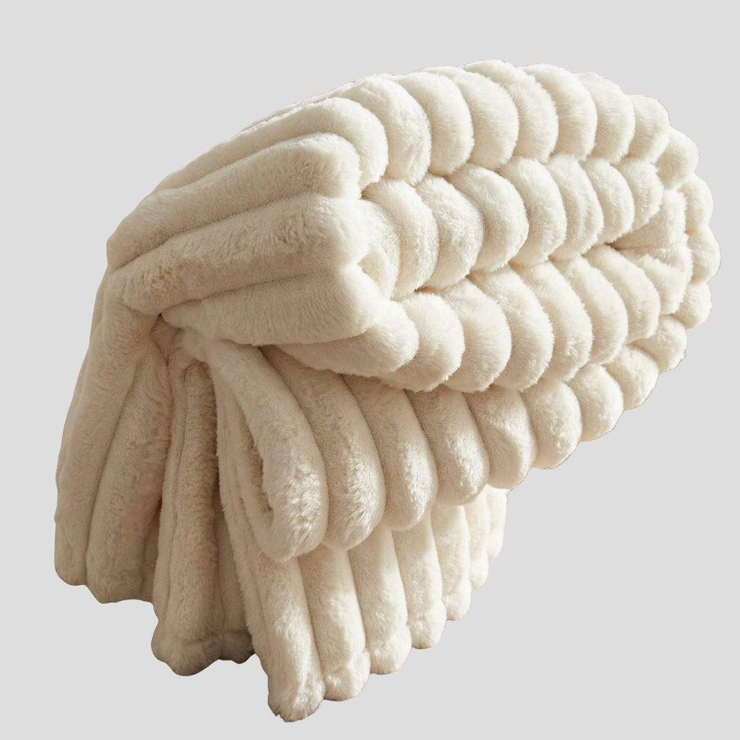 Złożony miękki koc pluszowy w odcieniu ivory pokazujący puszystą teksturę