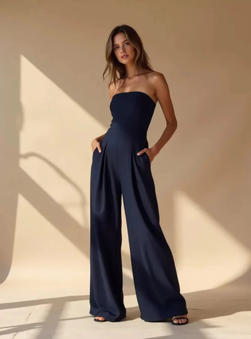 Kobieta w eleganckim granatowym kombinezonie bez ramiączek z szerokimi nogawkami