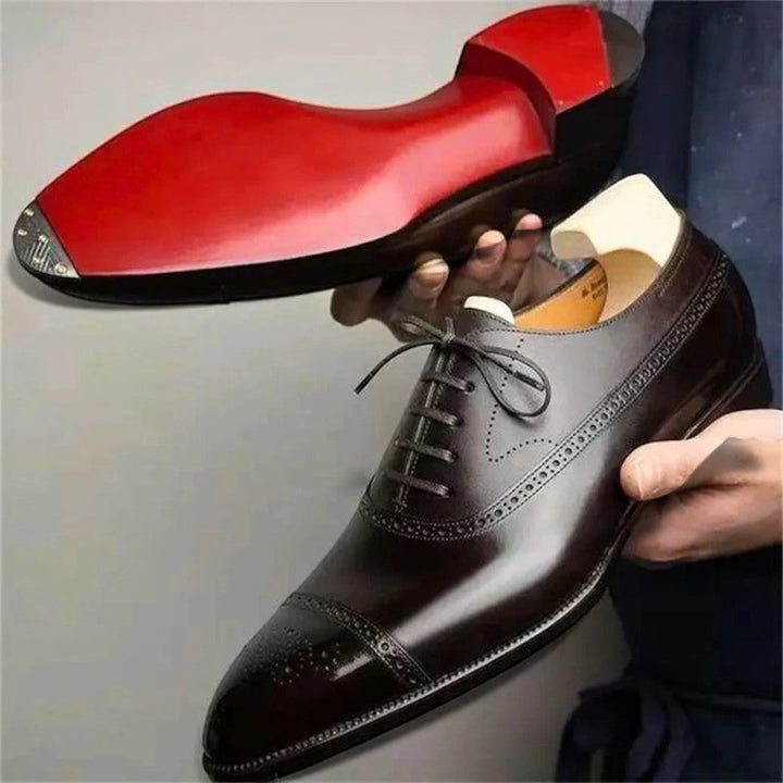 Brązowe męskie buty wizytowe trzymane w dłoni z widoczną podeszwą