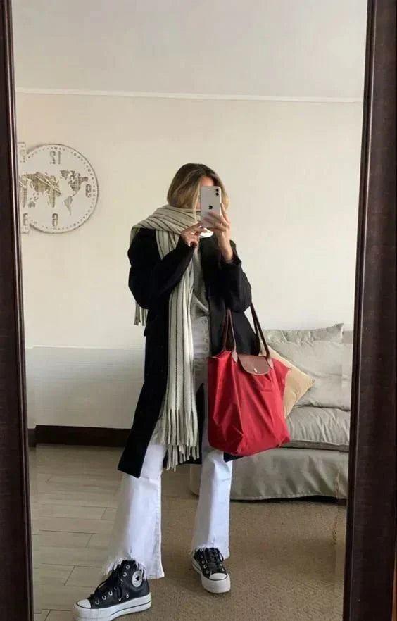 Kobieta przed lustrem trzymająca czerwoną elegancką torebkę damską