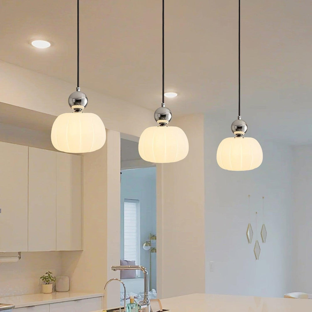 Zestaw trzech lamp wiszących zamontowanych nad blatem w nowoczesnej kuchni