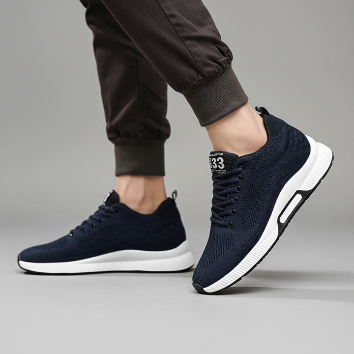 Mężczyzna w ciemnych spodniach prezentujący granatowe sneakersy podwyższające Andrew z białą podeszwą