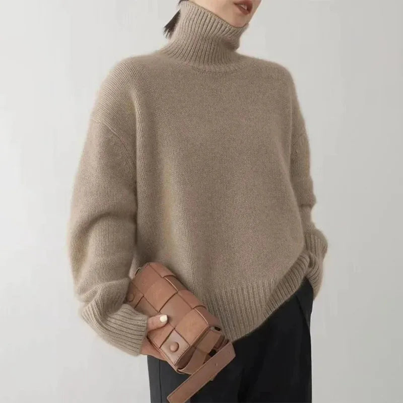 Kobieta w brązowym swetrze z golfem trzymająca elegancką torebkę
