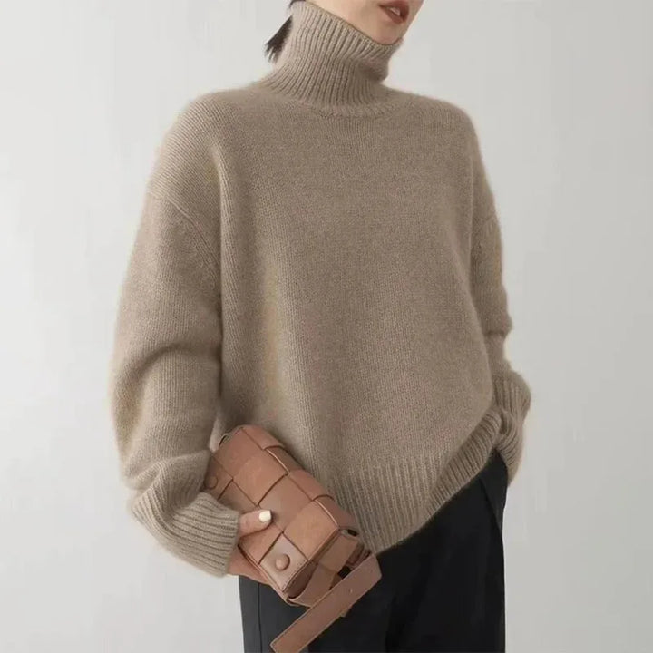 Kobieta w brązowym swetrze z golfem trzymająca elegancką torebkę