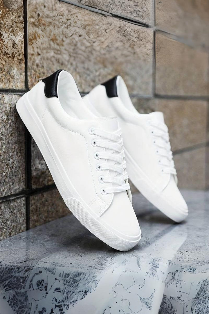 Męskie białe sneakersy Oliwier prezentowane na tle kamiennej ściany