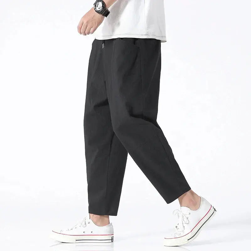 Mężczyzna w czarnych spodniach tapered cropped z białymi tenisówkami
