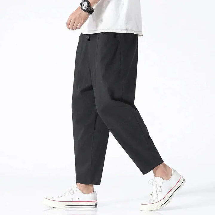 Mężczyzna w czarnych spodniach tapered cropped z białymi tenisówkami