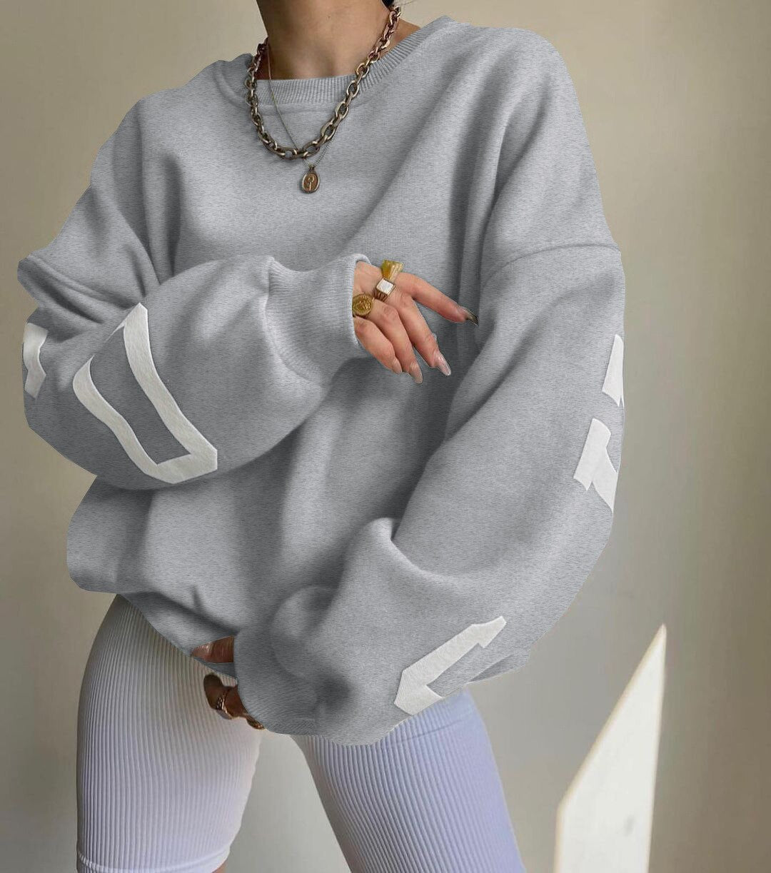 Kobieta w jasnoszarej bluzie oversize z długim rękawem