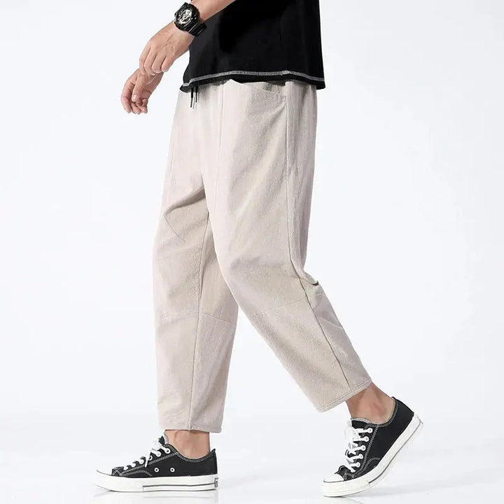 Mężczyzna w khaki spodniach tapered cropped z czarnymi tenisówkami