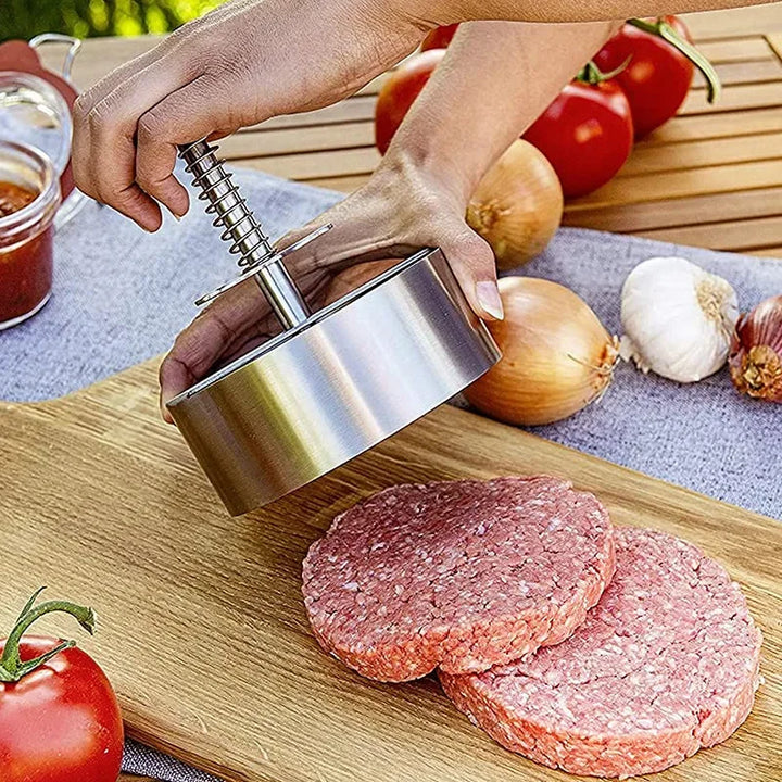 Osoba formująca mięsny kotlet za pomocą metalowej prasy do burgerów