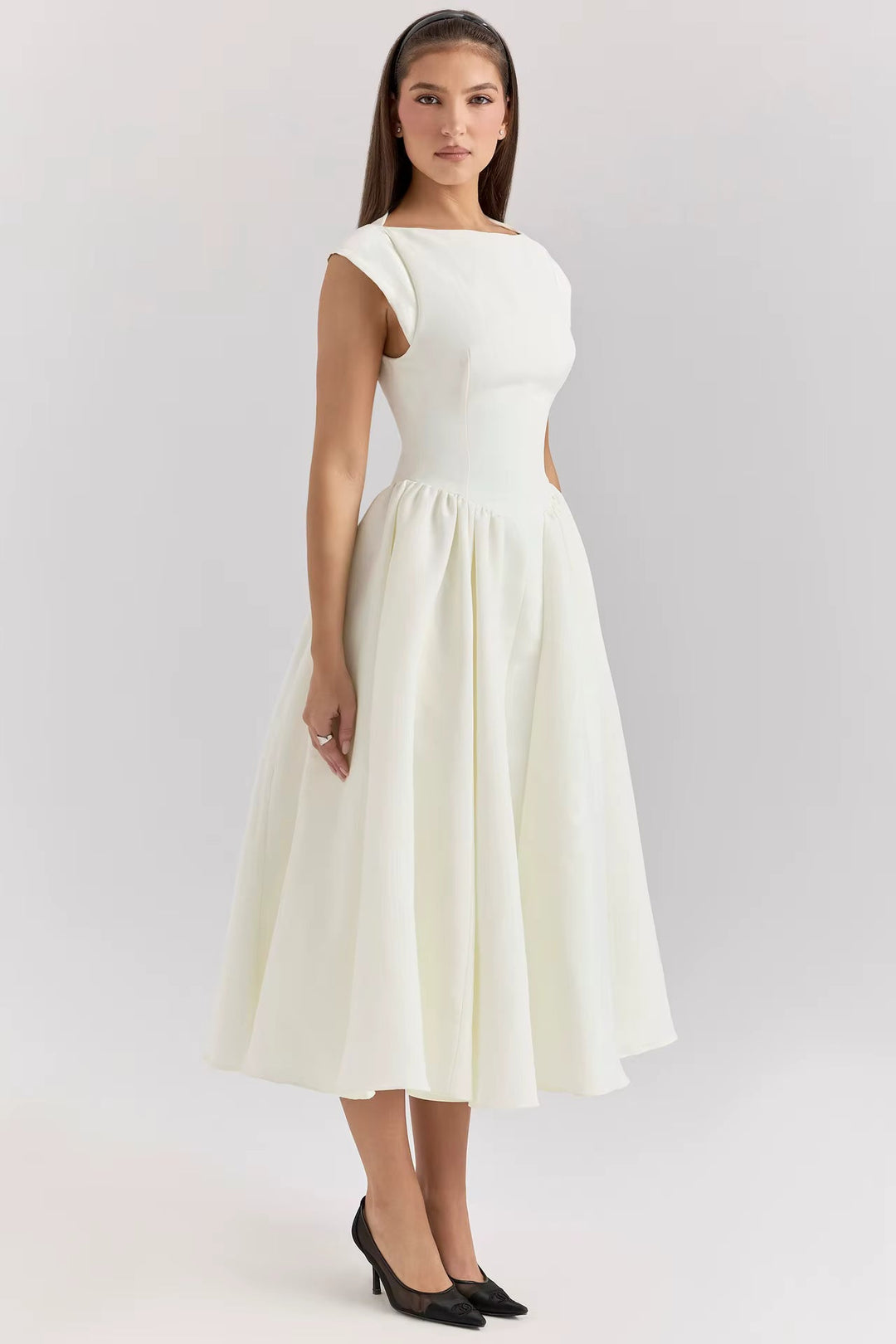 Modelka prezentująca białą elegancką sukienkę midi z krótkim rękawem