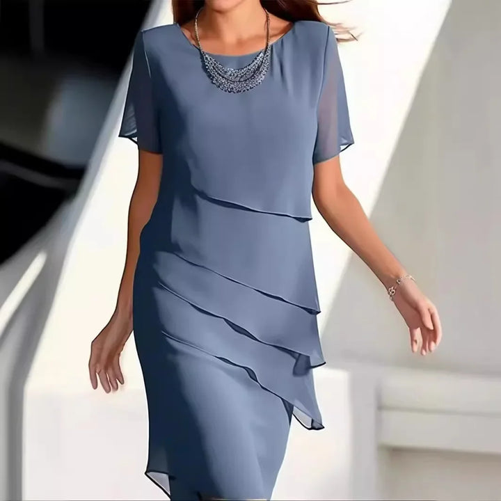 Modelka w niebieskiej eleganckiej sukience warstwowej z krótkim rękawem