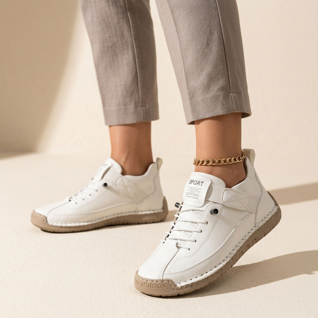 Białe wsuwane sneakersy damskie na nodze w jasnych spodniach