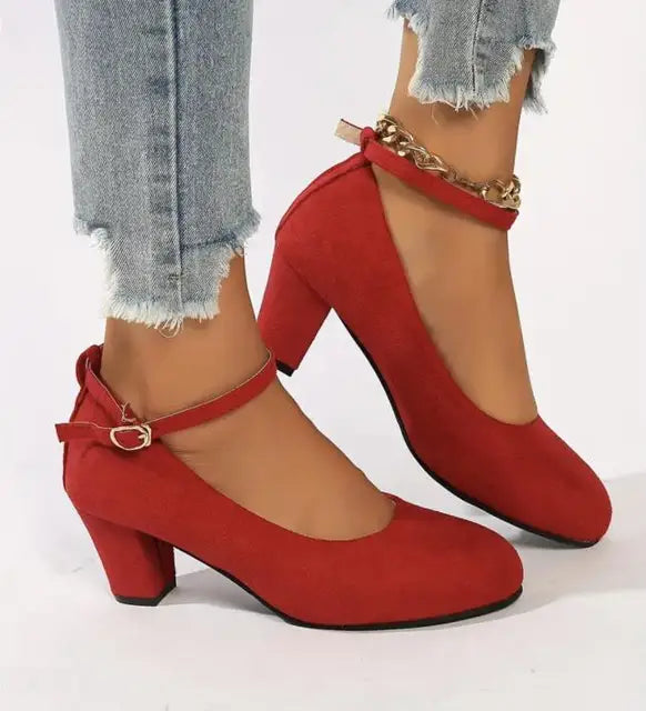 Czerwone eleganckie buty damskie z paskiem wokół kostki prezentowane na stopie