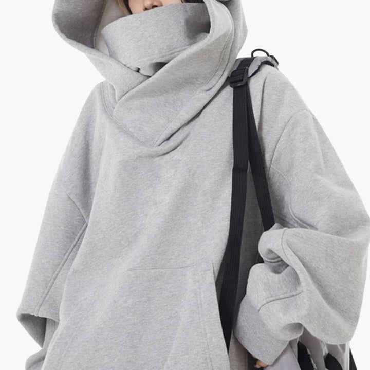 Kobieta w szarej bluzie oversized z kapturem i plecakiem w plenerze