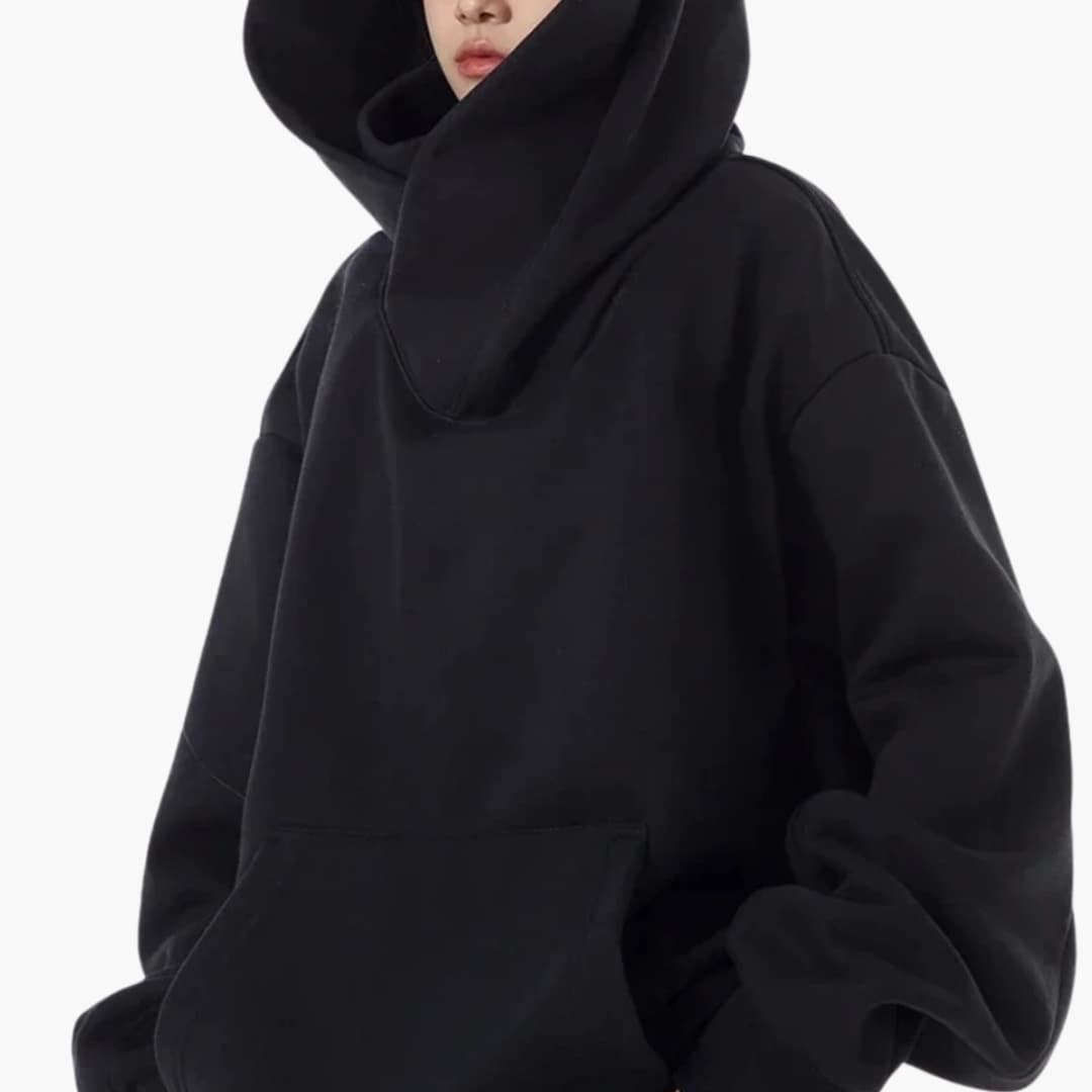 Kobieta w czarnej bluzie oversized z kapturem prezentująca wysoki kołnierz