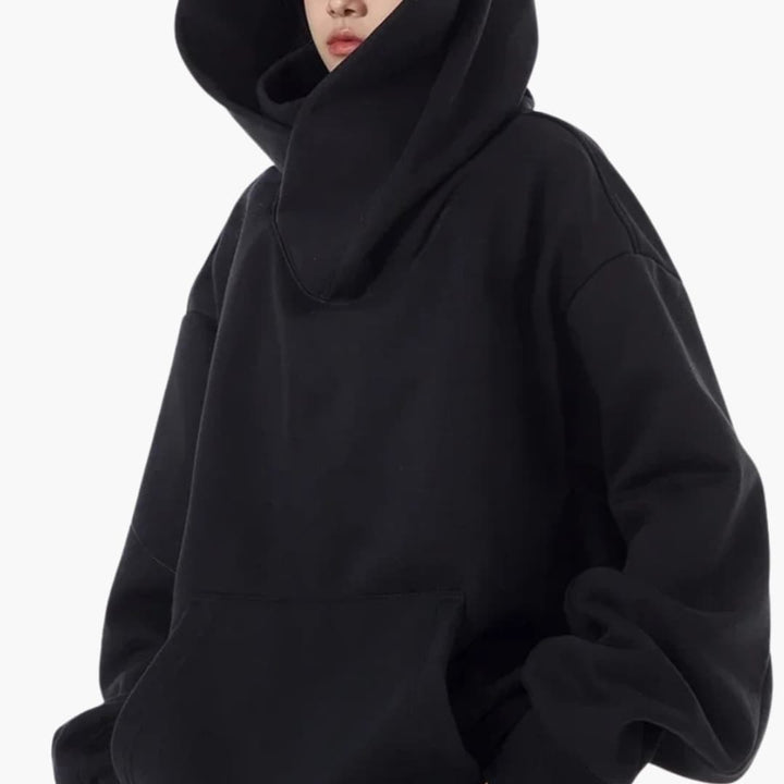 Kobieta w czarnej bluzie oversized z kapturem prezentująca wysoki kołnierz