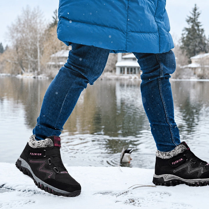Kobieta w czarnych ocieplanych sneakersach zimowych idąca po śniegu nad wodą