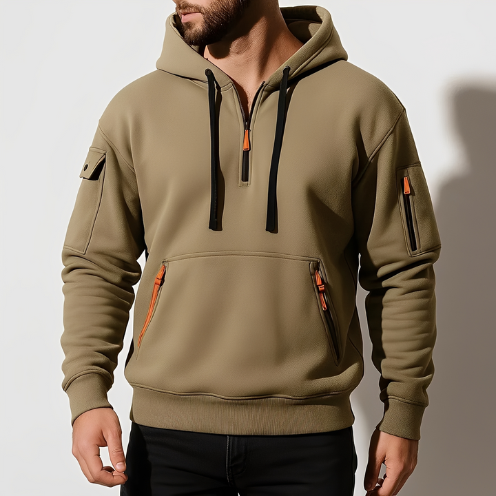 Mężczyzna w khaki bluzie z kapturem i półzamkiem prezentujący sportowy krój