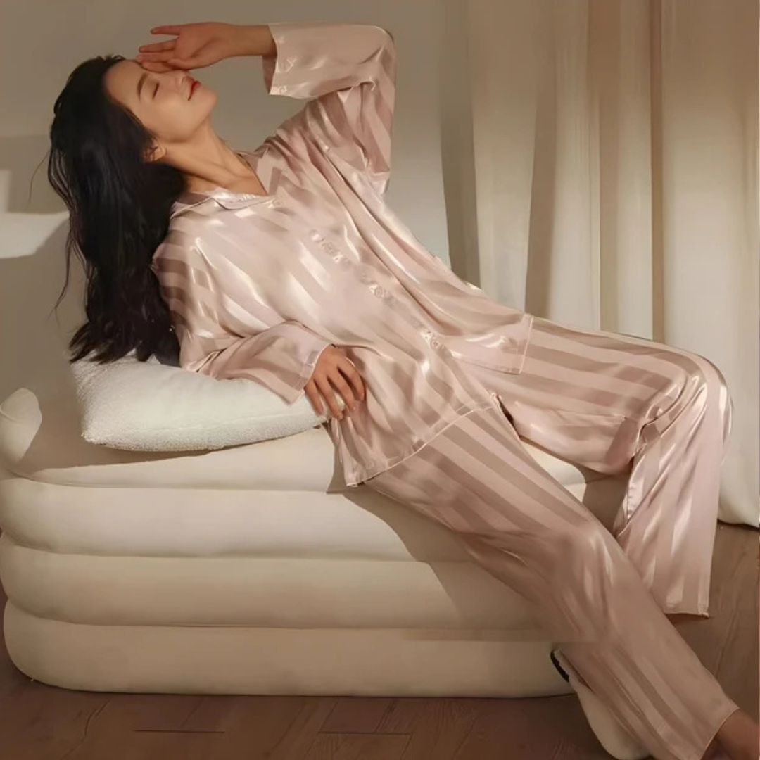 Kobieta leżąca na jasnej kanapie w eleganckiej piżamie w paski
