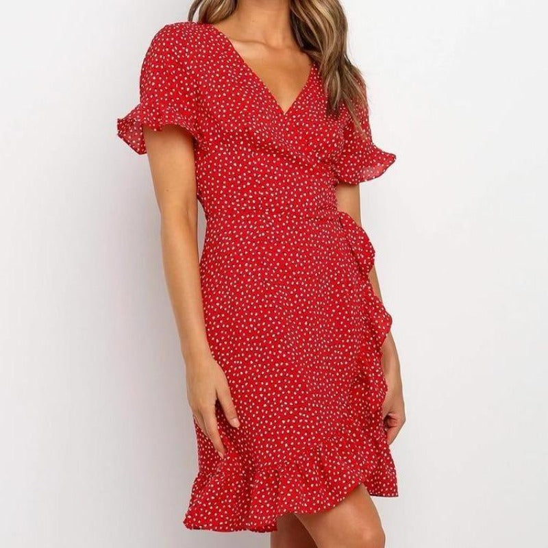Lekka damska sukienka mini w czerwone kropki z ozdobnym wiązaniem, rozcięciem, modna letnia stylizacja.