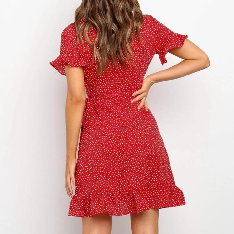 Elegancka czerwona sukienka mini w białe kropki, wiązana w pasie, z falbanką i seksownym rozcięciem.