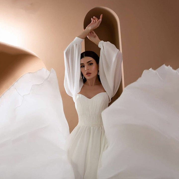 Stylowa damska sukienka maxi na wesele, biała, z długim rękawem i eleganckim dekoltem off-shoulder.
