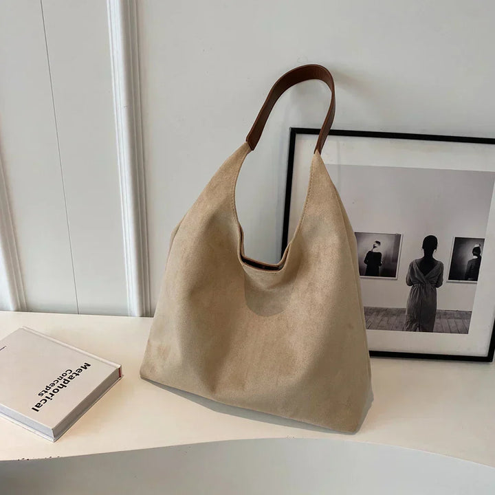 Kobieta z modną torbą shopper z zamszu na ramieniu, idealna do miejskich stylizacji.