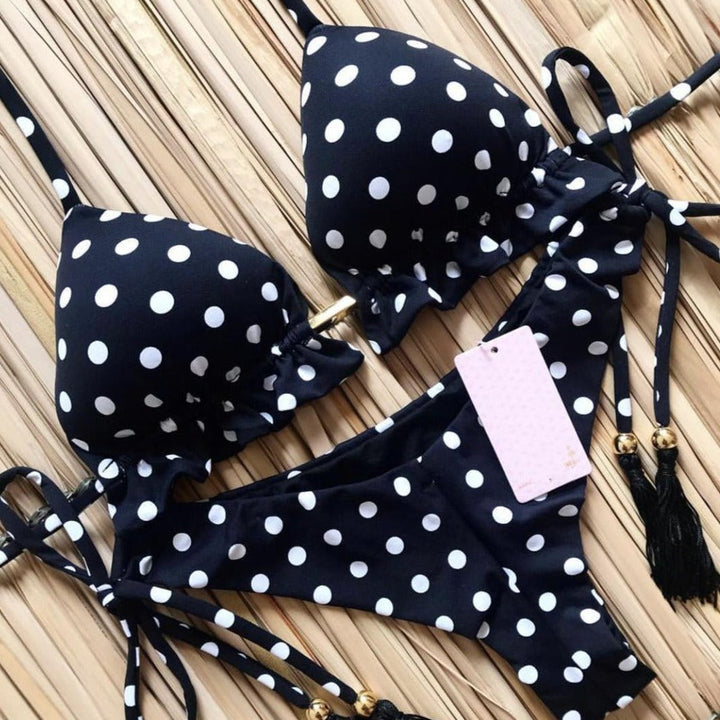Kobieta w stylowym dwuczęściowym bikini z modnymi wzorami, ciesząca się słońcem na plaży.