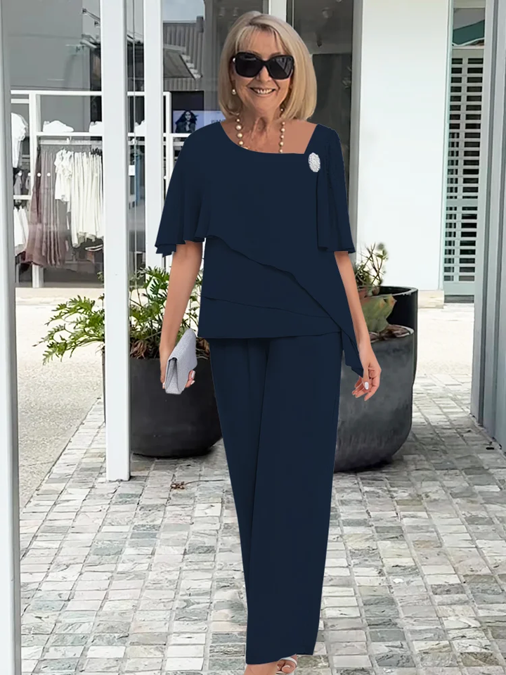 Kobieta w eleganckim granatowym garniturze z tuniką i torebką