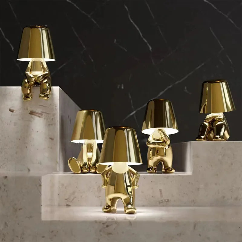 Złota lampa stołowa LED o unikalnym kształcie figurki w eleganckim wnętrzu