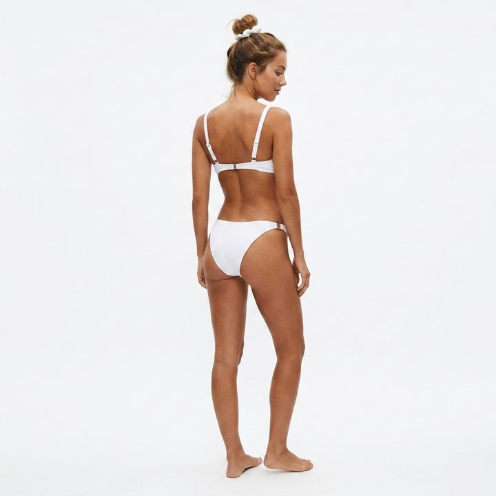 Widok z tyłu na modelkę w białym bikini plażowym z ozdobnymi kółkami